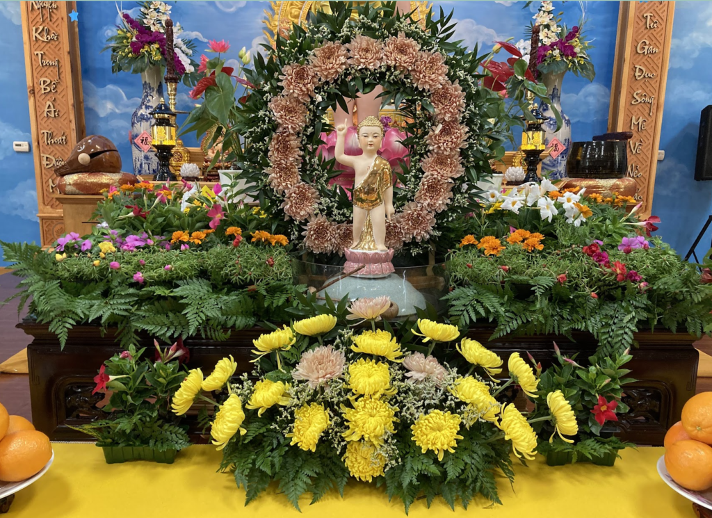 Image: a statue of the Baby Buddha-to-Be, surrounded by flowers. 